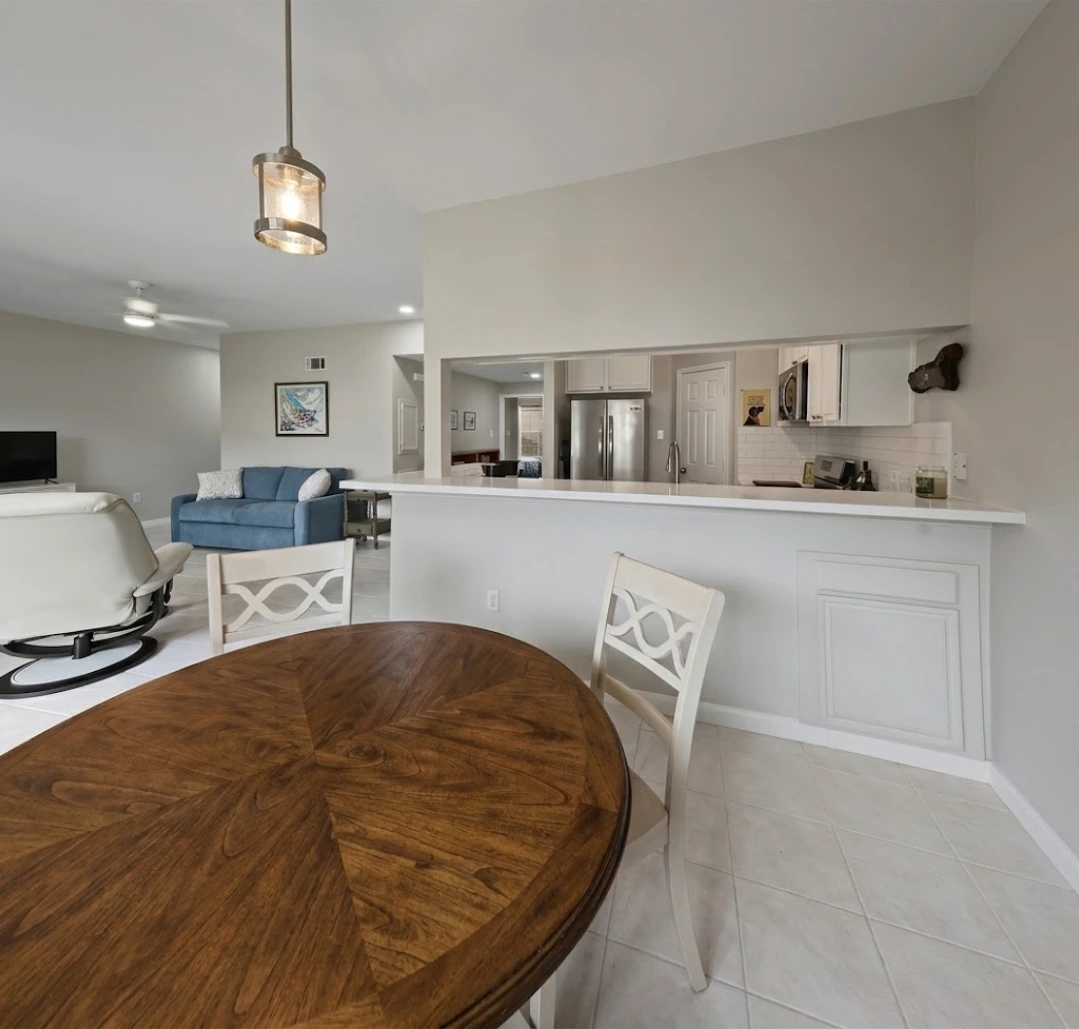 Clean restored open-plan home interior in Baytown with a kitchen breakfast bar, dining table and tile flooring after water damage restoration